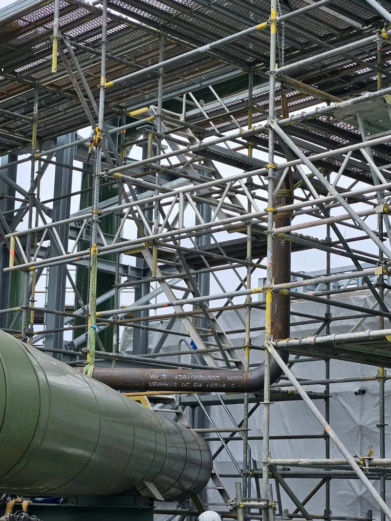 Eingerüstete Industrieanlage mit Stahlrohrleitung und isolierter Leitung